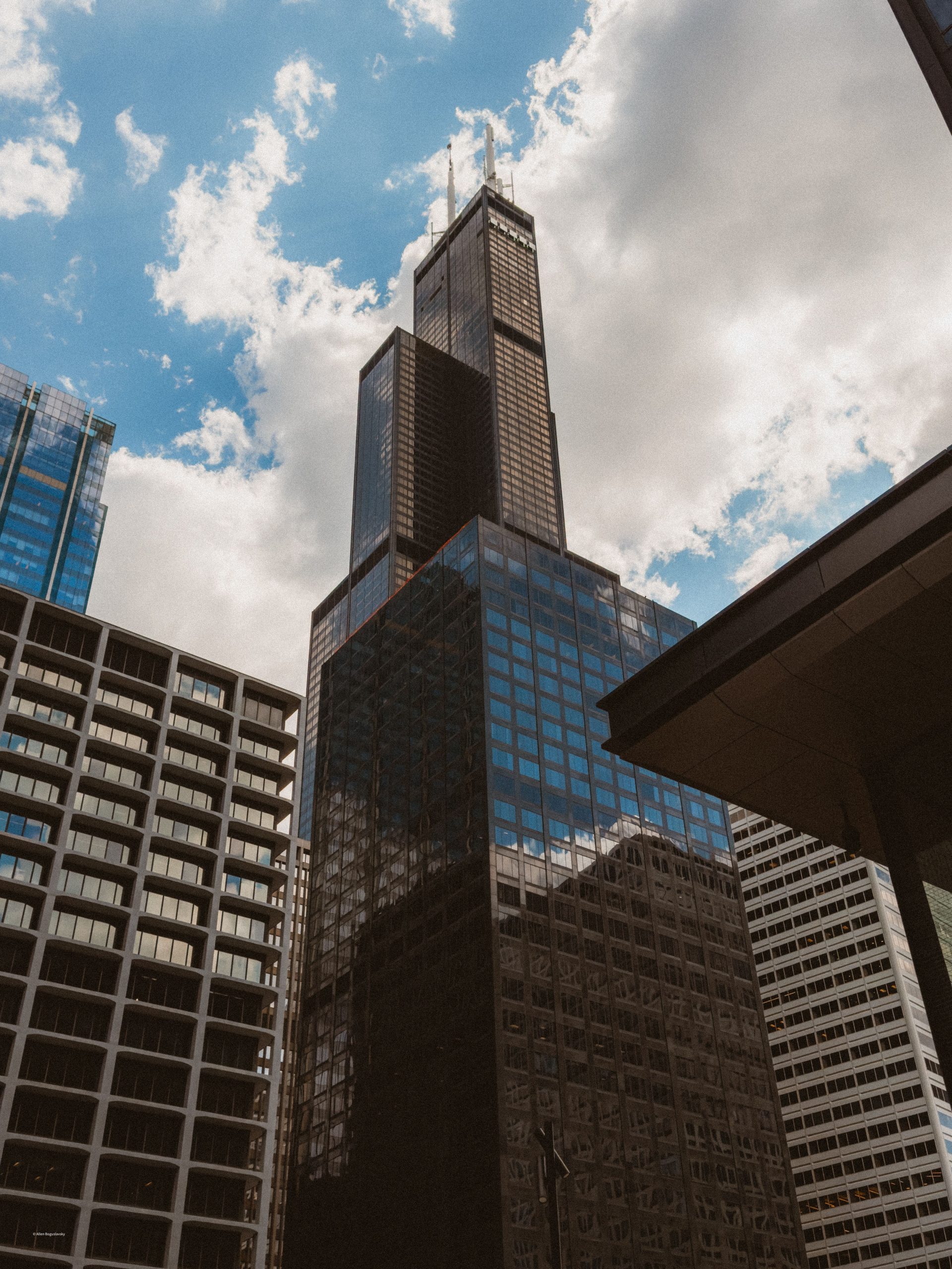 Tall skyscraper against blue sky with clouds in downtown Chicago, iconic architecture.